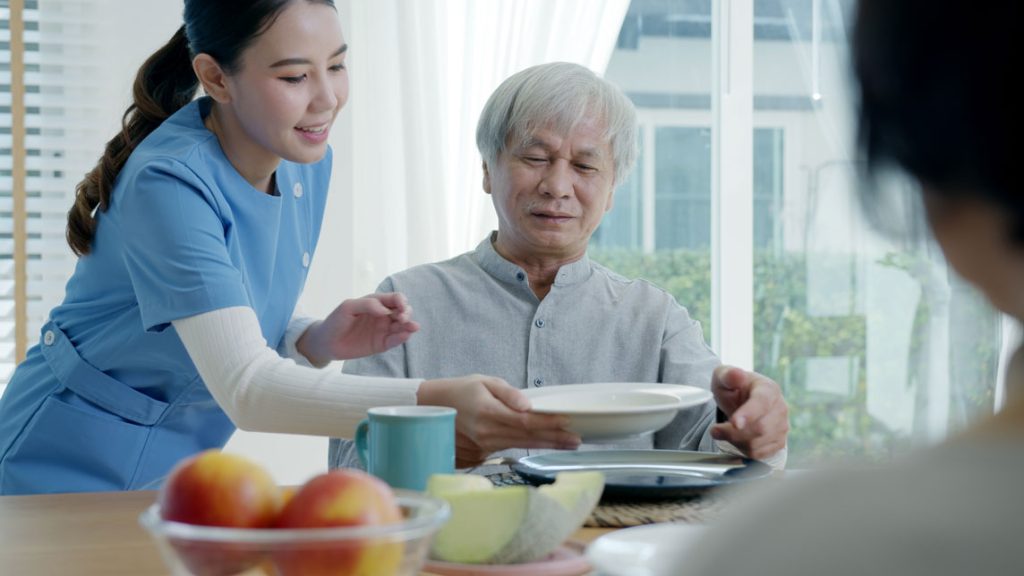 Girl helping an old man at the table