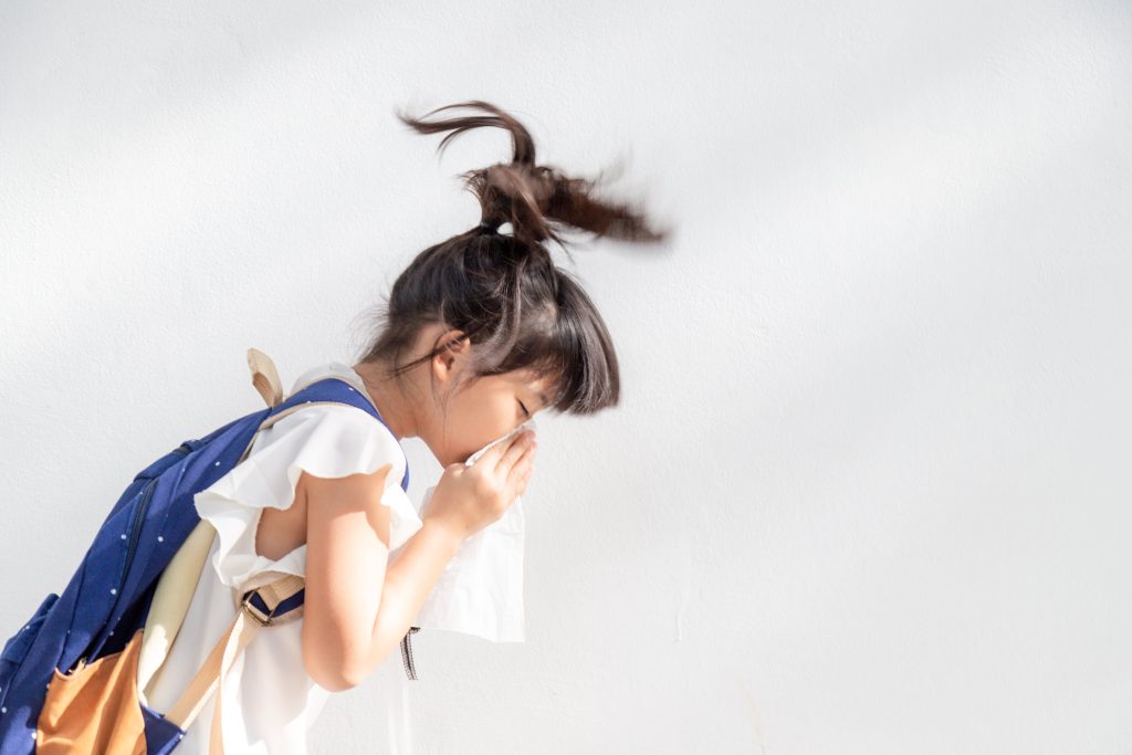 young girl sneezing on a handkerchief