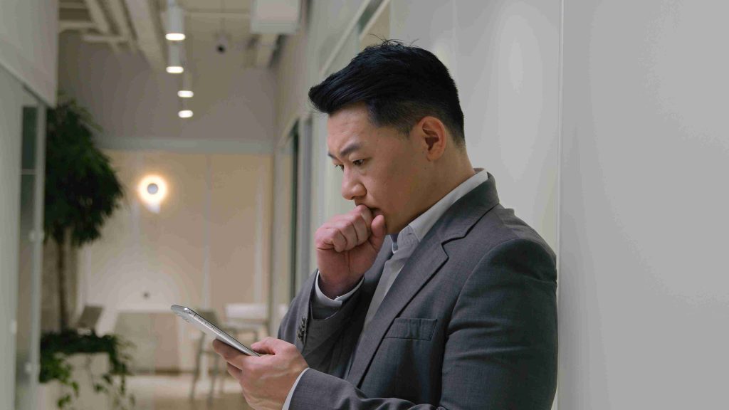 asian man trying to understand what he is reading on his mobile phone