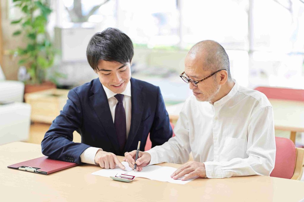 old asian man signing a document with his lawyer