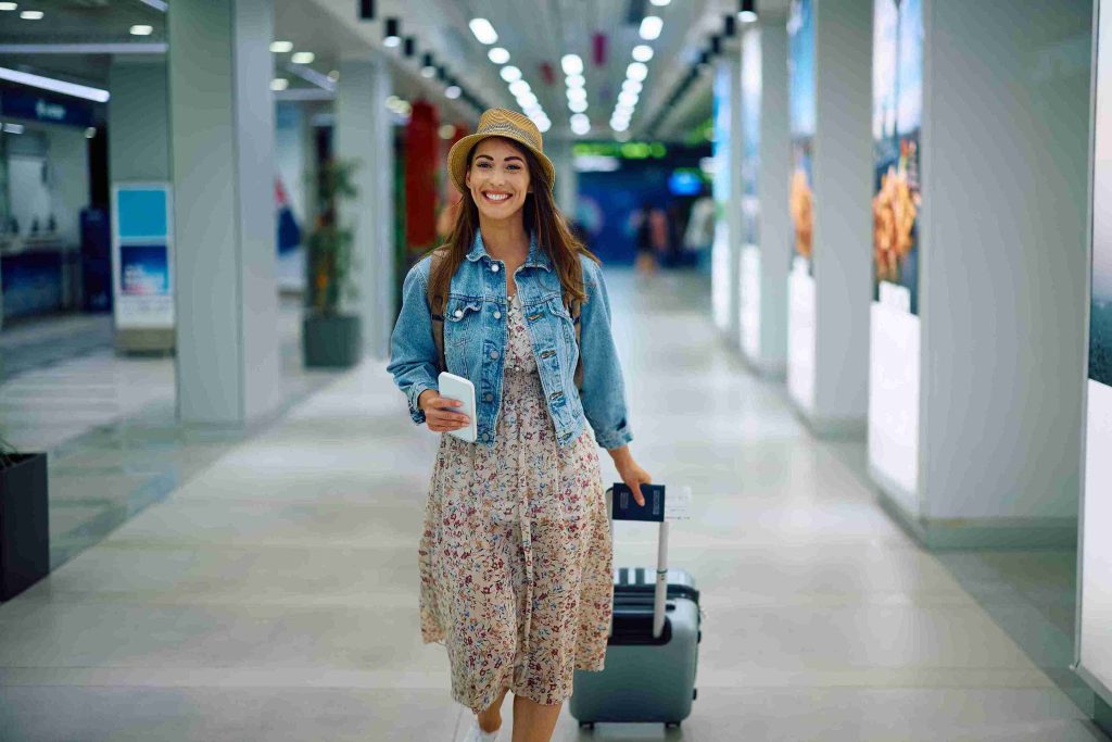 young female smiling and pulling her luggage in the airport