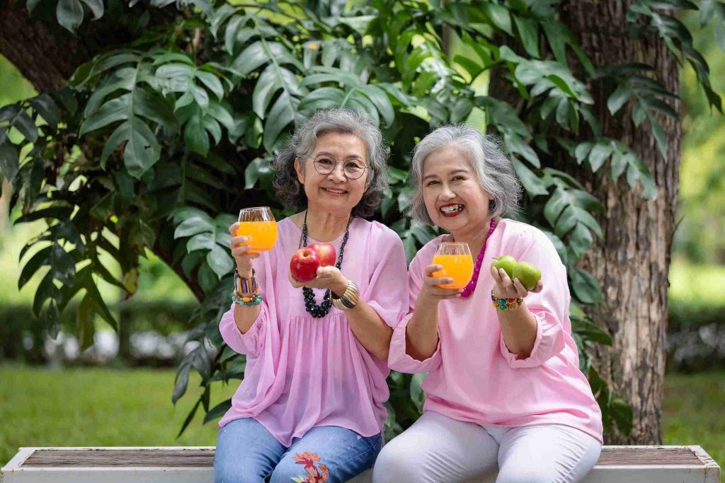 two elderly women carrying fruits and orange juice