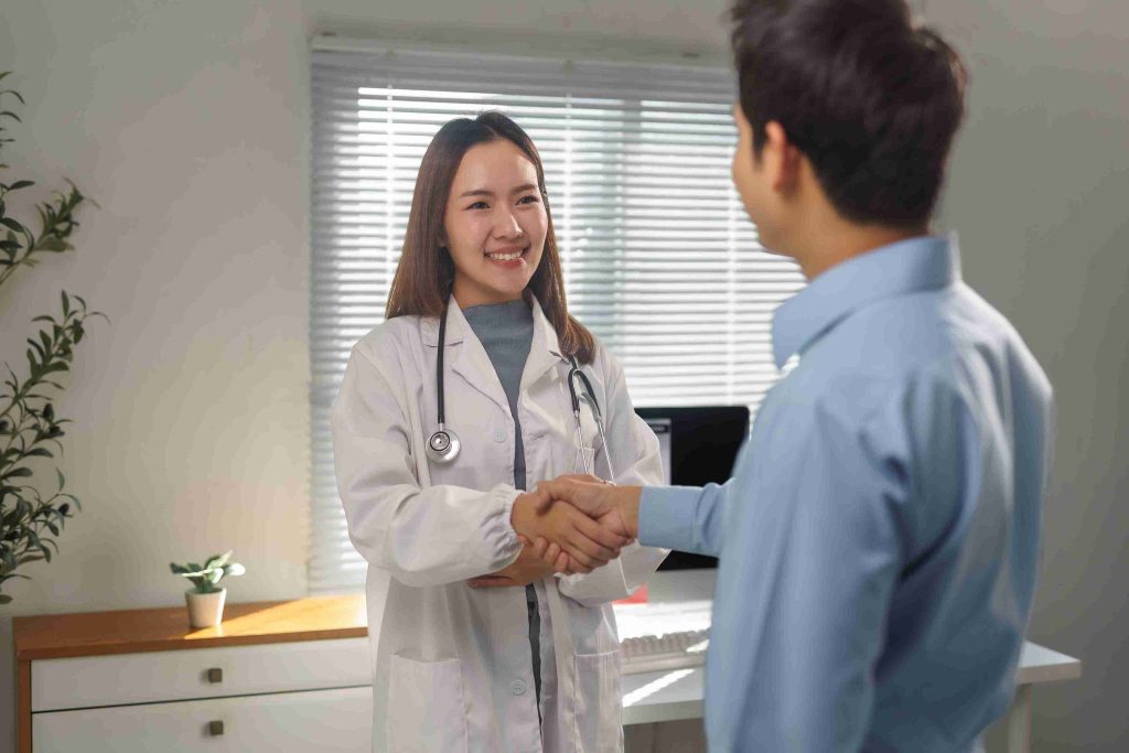 Female doctor shaking hands with a male patient.