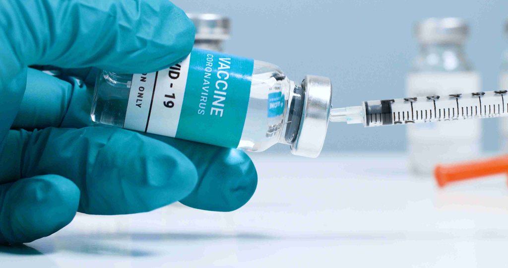 Healthcare worker holding a COVID vaccine vial.