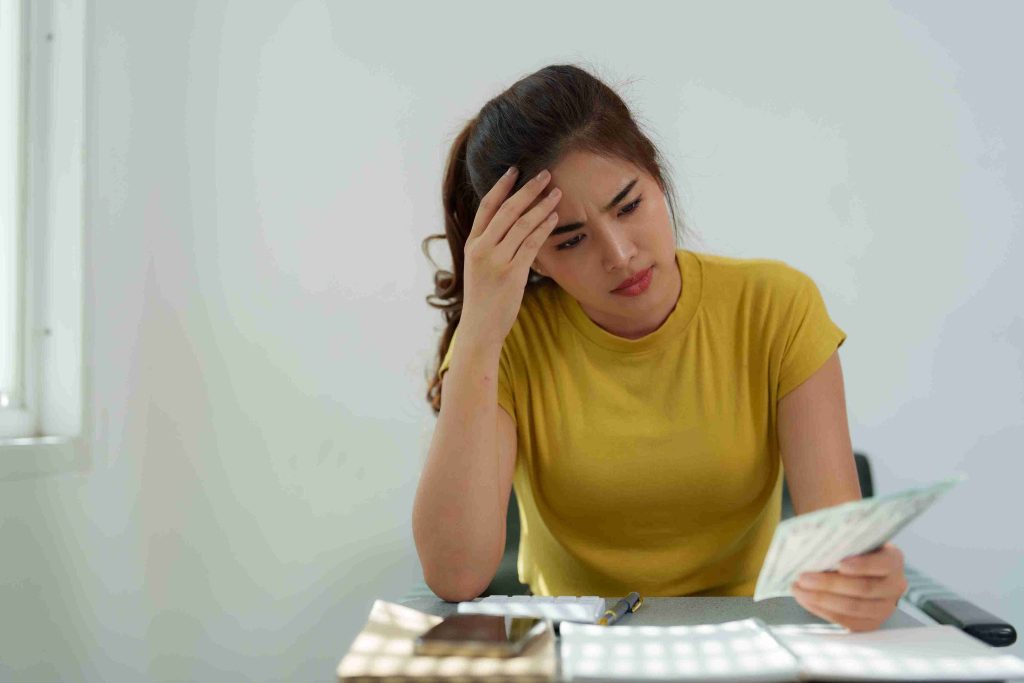Woman holding money and looking worried.